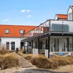 House with balcony and red roof, surrounded by dry grass.