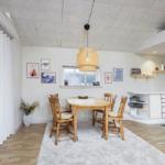 Esszimmer mit Holztisch, vier Stühlen und Küchenbereich im Hintergrund.