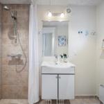 Badezimmer mit Dusche, Waschbecken und Spiegel.