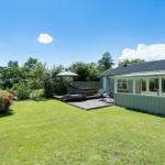 Haus mit Garten, Terrasse und Sonnenschirm. Grünfläche und Blumenbeete.
