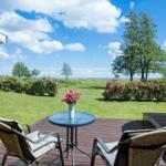Terrasse mit Tisch und Stühlen, Blick auf grünen Garten und Horizont.