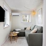 Ein Wohnzimmer mit Sofa, Fernseher und zwei Fenstern.