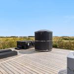 Holzterrasse mit Whirlpool und Liegestühlen im Freien.