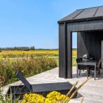 Terrasse mit Grill und Tisch. Blick auf Felder und Himmel.