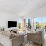 Wohnzimmer mit Sofa, Fernseher und Blick auf Terrasse.