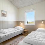 Zwei Betten mit weißen Decken, Fenster mit Blick auf Feld, Wandbilder und Holzboden.
