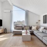 Living room with gray sofa, TV, and large window.