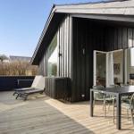 Deck with table, chairs, and loungers in front of a modern wooden house.