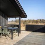 Deck with table and chairs, view of forest and sky.