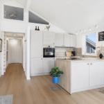 Kitchen with island, stove, and oven. Wooden floor and white walls.