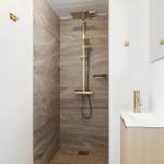 Shower with gold fixtures and stone wall. Sink with gold faucet.
