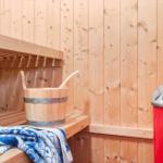 Sauna with wooden walls, bench, bucket, and towel.