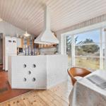 Kitchen with white cabinets and brick island. Wooden floor and large windows.