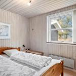 Bedroom with wooden paneling, bed, window, and wall art.