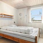 Bedroom with wooden bed, window, and wall shelf.