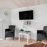 Living room with TV, two chairs and table. Wooden ceiling and window with view.