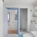 Bathroom with shower, toilet, and window. Door leads to living area.