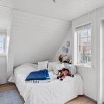 Bedroom with white wood walls, bed, windows, and toys.