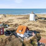 House with red roof and white facade by the coast