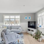 Living room with sofa, TV, and windows.