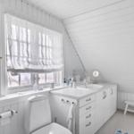 Bathroom with white fixtures, window, and sink.