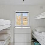 Room with two bunk beds, white dresser, and window with outdoor view.