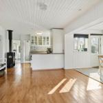 Living kitchen with wooden floor, white walls, and wood stove.