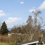 House with view of forest and sky with clouds.