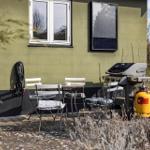 Terrace with table, chairs, and grill against house wall.