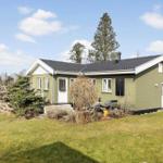 Green house with garden and grill area under blue sky.