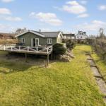 Green house with terrace and garden. Background: other houses and trees.