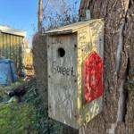 Wooden birdhouse on tree with inscription Love Sweet Home and red heart