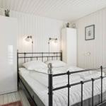 Bedroom with metal bed, white walls, and window.