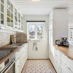 Kitchen with white cabinets, wooden surfaces, and window view of outdoor area.