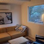 Wohnzimmer mit Sofa, Tisch und Fenstern zur Außenseite.