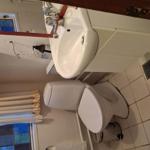 Badezimmer mit Toilette, Waschbecken und Fenster mit bunten Fliesen.