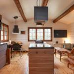 Küche mit Essbereich und Wohnzimmer mit Holzdielen und Balken.