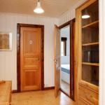 Flur mit Holztüren und Schrank. Blick in Schlafzimmer mit Bett.
