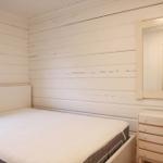 Schlafzimmer mit Bett, Schrank und Spiegel an weiß verputzten Wänden.