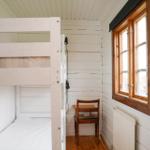 Kammer mit Doppelstockbett, Holzfenster und Stuhl.
