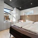 Schlafzimmer mit Doppelbett, Holzverkleidung, Fenster und Schränken.