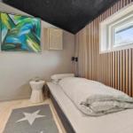 Schlafzimmer mit Bett, Wandbild und Holzverkleidung. Fenster und Bodenbelag sichtbar.