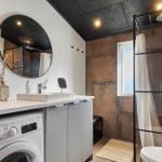 Badezimmer mit Dusche, Waschmaschine und Spiegelschrank.