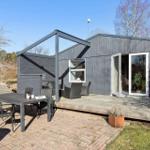 Moderne Holzhütte mit Terrasse und Sitzgelegenheiten im Freien.