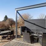 Terrasse mit Tisch, Stühlen und Sitzbereich unter Pavillon. Holzdecke und dunkle Wände.