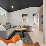 Wohnzimmer mit grafer Sofa, Holztisch und Fernseher an Holzwand.