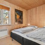 Schlafzimmer mit Holzwand, Bett und Fenster mit Blick auf Wald.