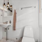 Badezimmer mit Waschbecken, Spiegel und Toilette. Fenster mit Blick nach draußen.