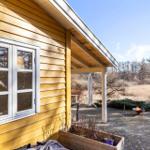 Gelbes Holzhaus mit Terrasse und brennendem Feuerkorb im Garten.