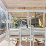 Esszimmer mit Tisch, Stühlen und großem Fensterblick auf Wald